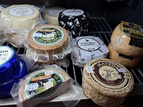 Surtido de quesos envasados ​​expuestos en una estantería refrigerada de la tienda.