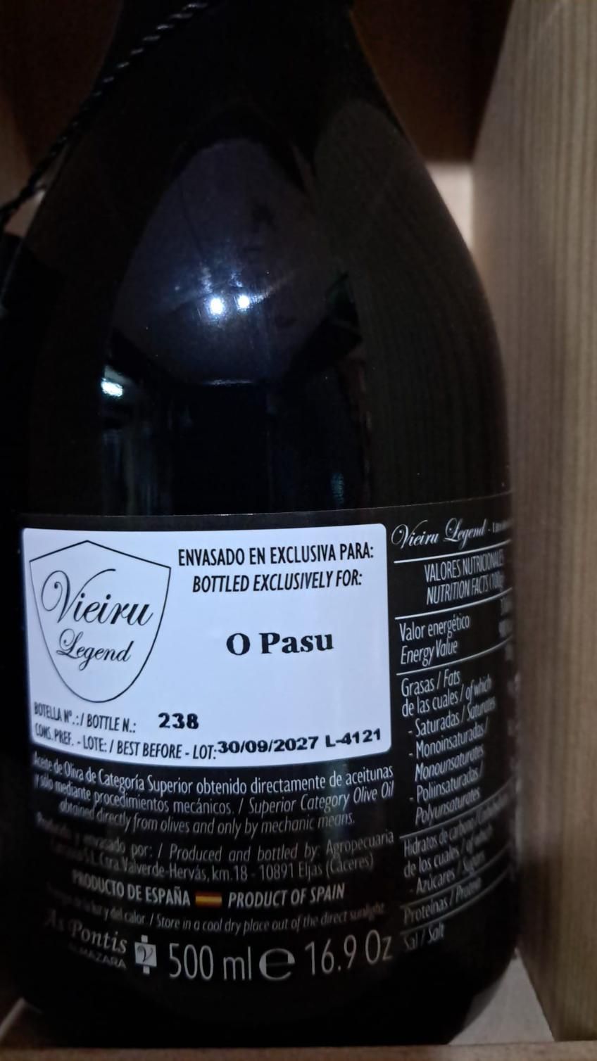 Primer plano de una botella de vino de vidrio oscuro con una etiqueta blanca y texto en negro y azul.