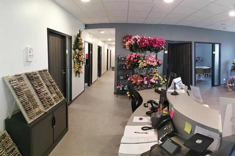 Bureau d'accueil moderne avec écrans d'ordinateur, présentoirs à brochures et présentoir à fleurs roses