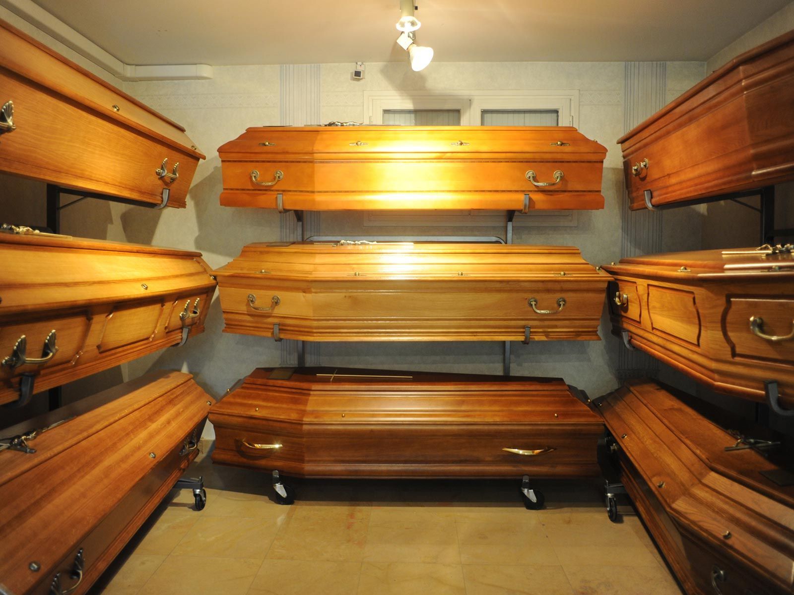 Salon funéraire confortable, tapissé de cercueils en bois poli sur les deux murs et empilés au centre.