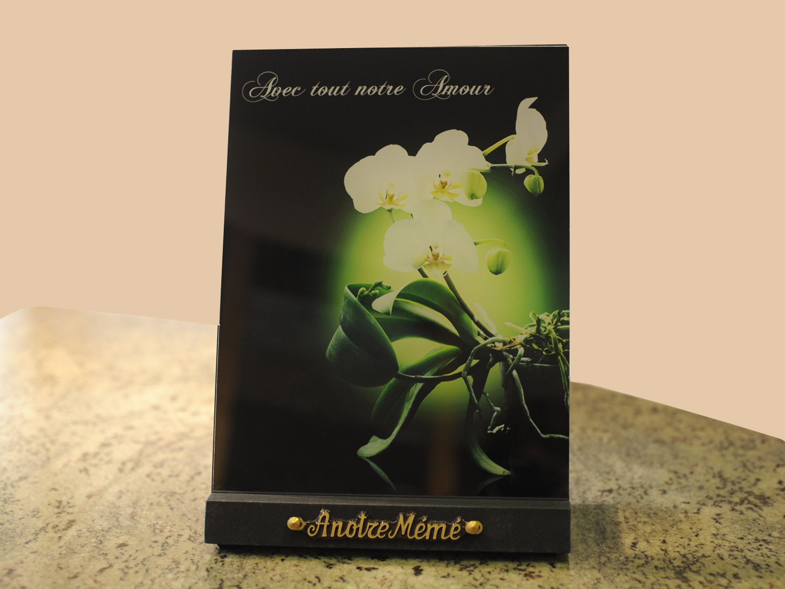 Plaque noire ornée de fleurs blanches et de feuilles vertes, posée sur une table.