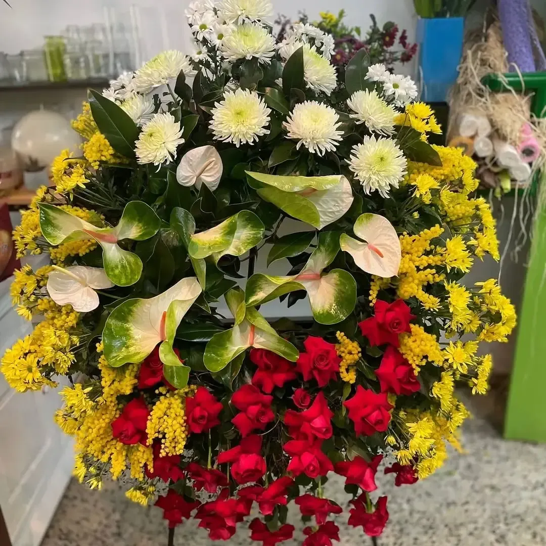 Un arreglo floral circular para funeral compuesto por crisantemos blancos, anturios de color rosa claro