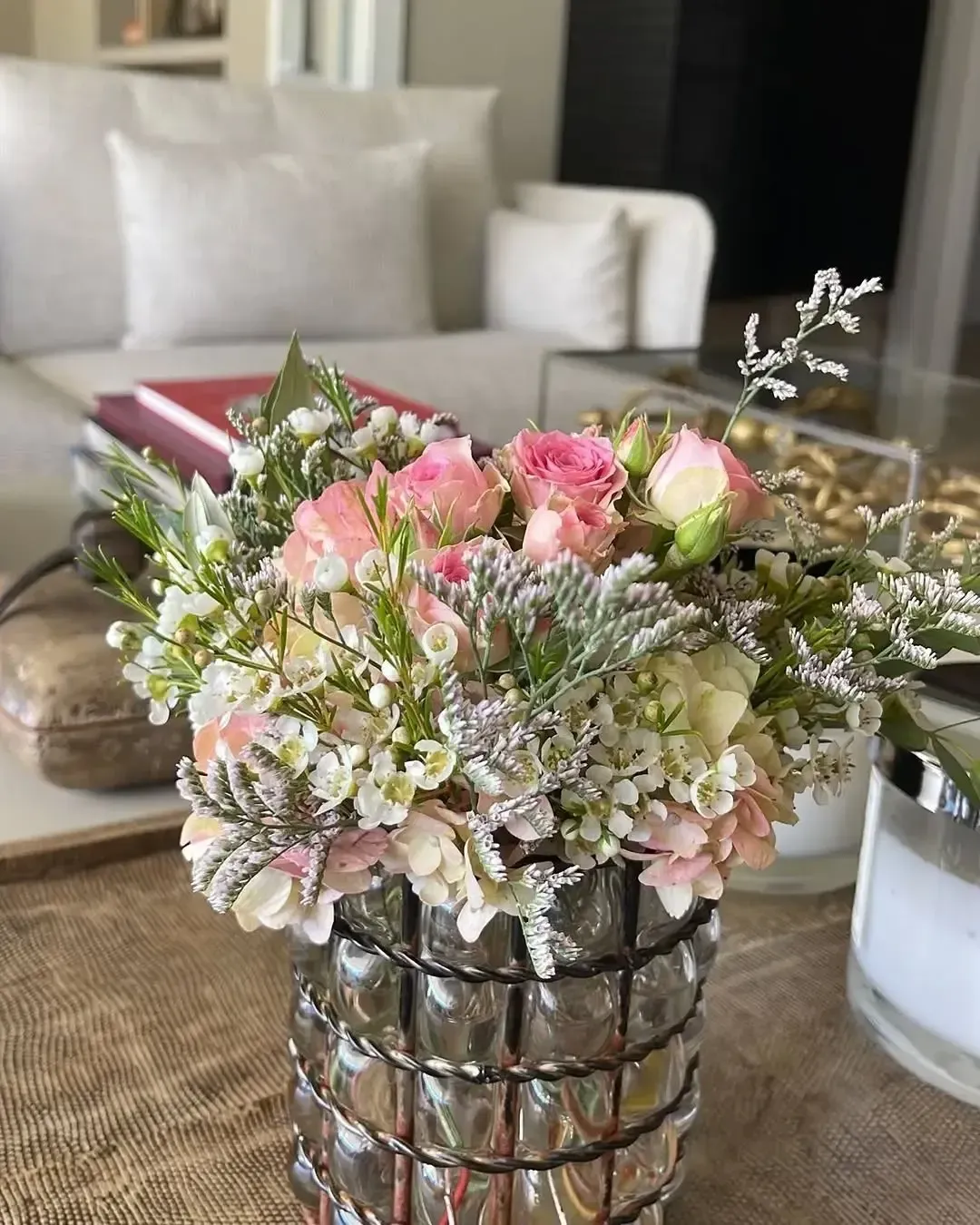 Un jarrón de cristal texturizado contiene un ramo de rosas rosadas, hortensias blancas y flores de relleno