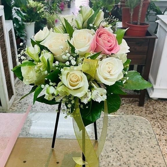 Un ramo redondo de una rosa blanca y una rosa rosa, adornado con paniculata y hojas verdes