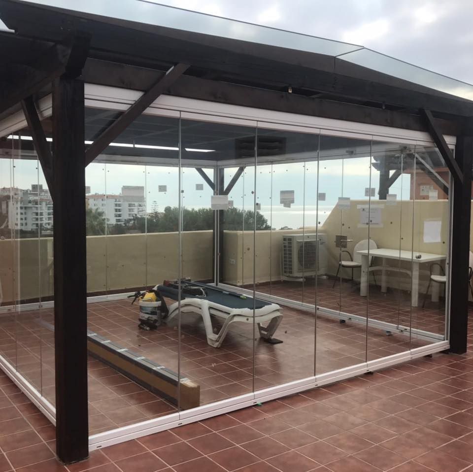 Un patio con una mesa de billar y sillas detrás de una pared de vidrio.