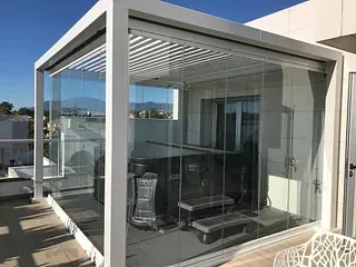 Una pérgola con puertas corredizas de vidrio y un jacuzzi en su interior.