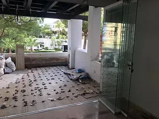 Una habitación con mucha basura en el suelo y una puerta de cristal.