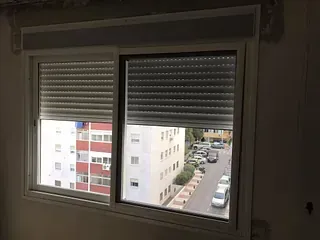 Una ventana con contraventanas y vista de una ciudad.