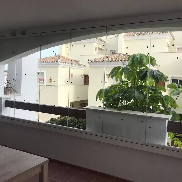 Un balcón con vista a un edificio y un árbol.