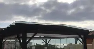 Una parada de autobús con techo de cristal y un cielo nublado al fondo.