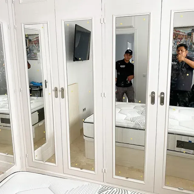 Un hombre se toma una foto en un espejo en un dormitorio.