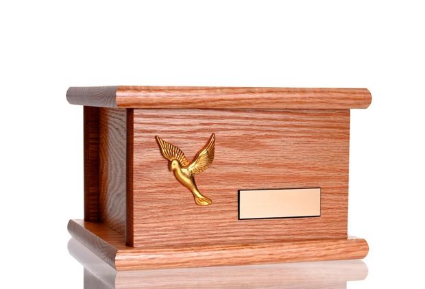 Una caja de madera con una paloma dorada encima.