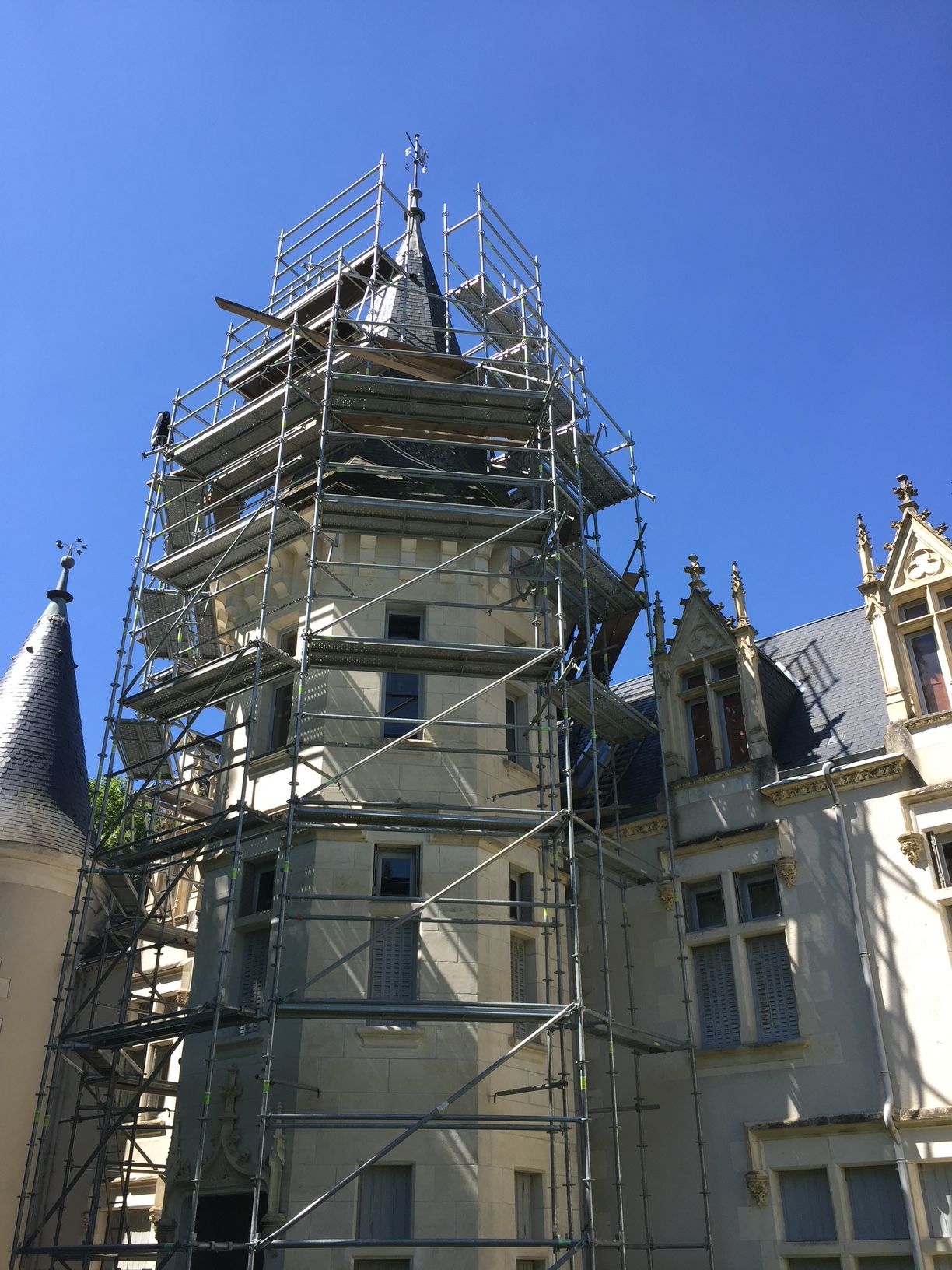 Échafaudage autour d'une tour du château Chènevière pour un chantier de rénovation de toiture