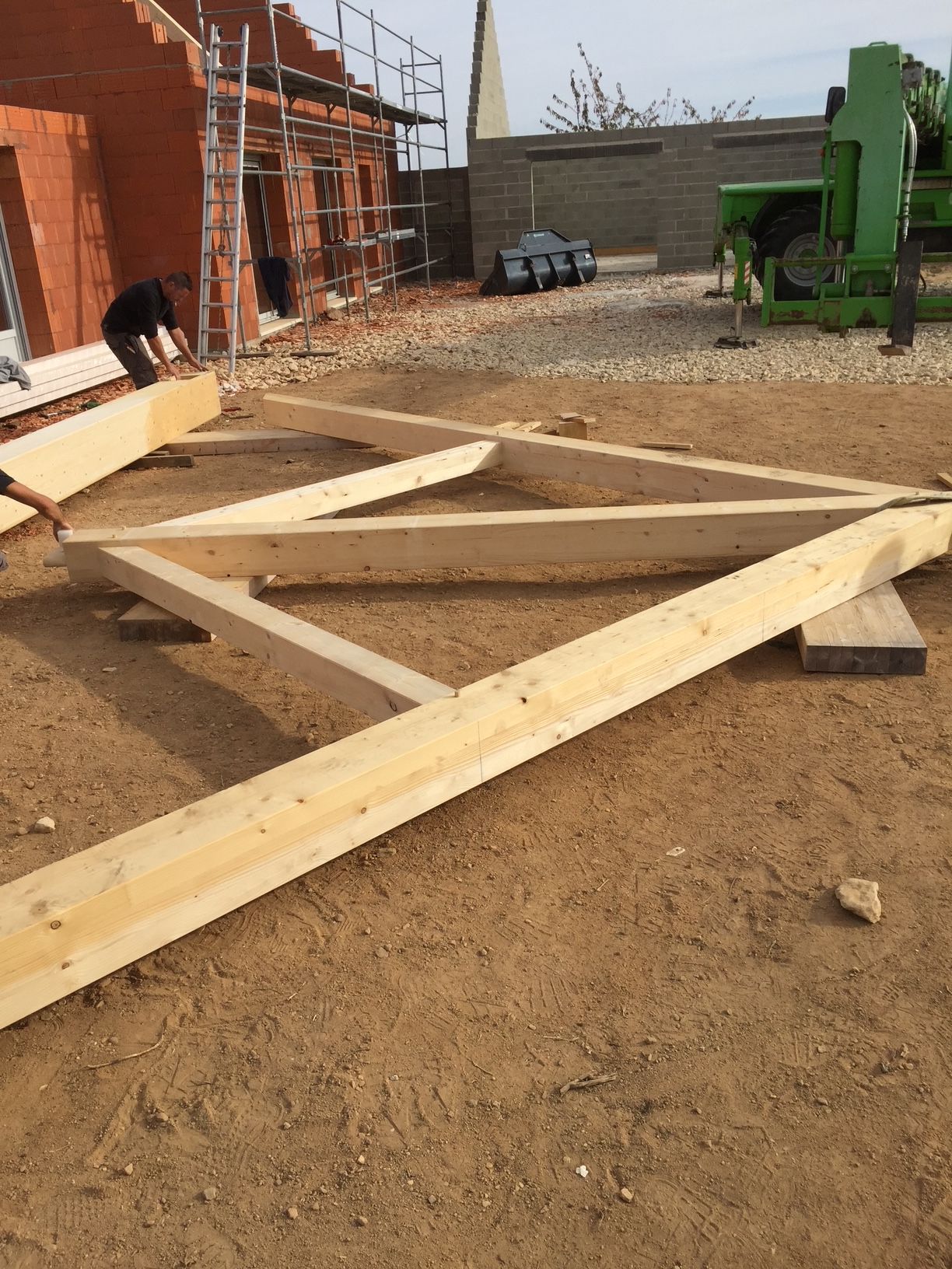 Partie de charpente en bois au sol à côté de miurs d'une maison en construction