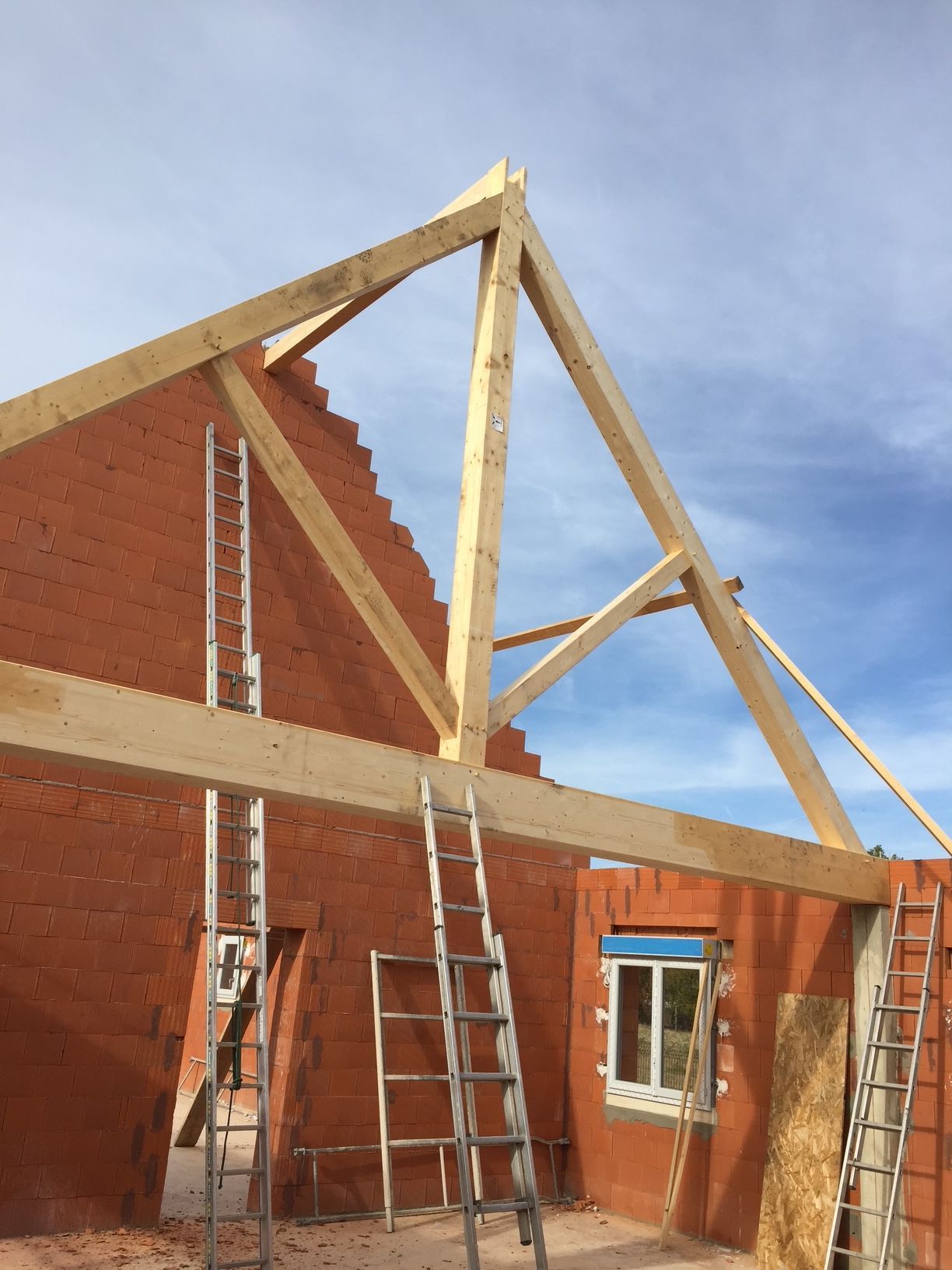 Chantier de maison en construction avec murs élevés et toiture manquante