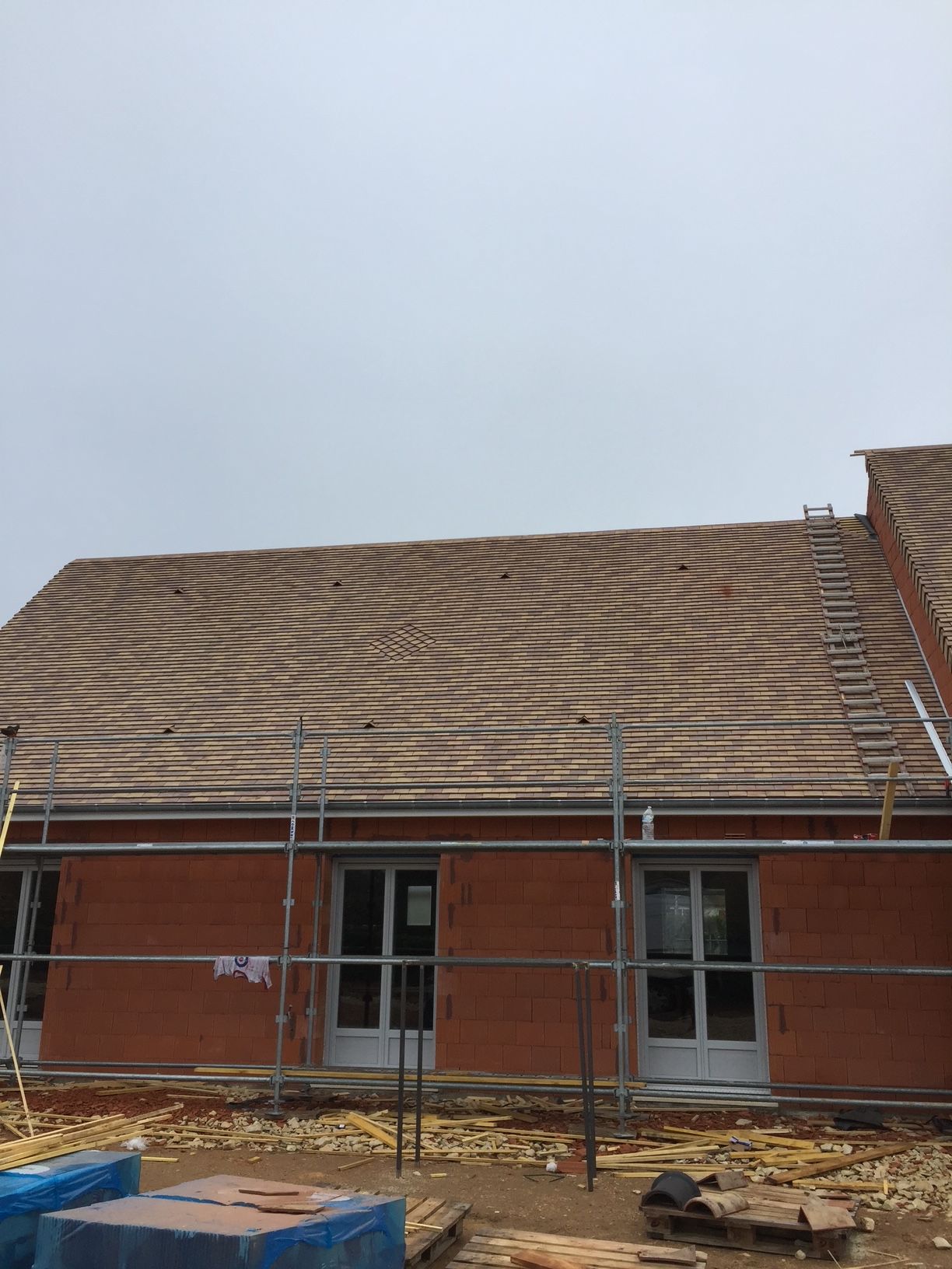 Échafaudage devant une maison en construction avec la toiture et les murs