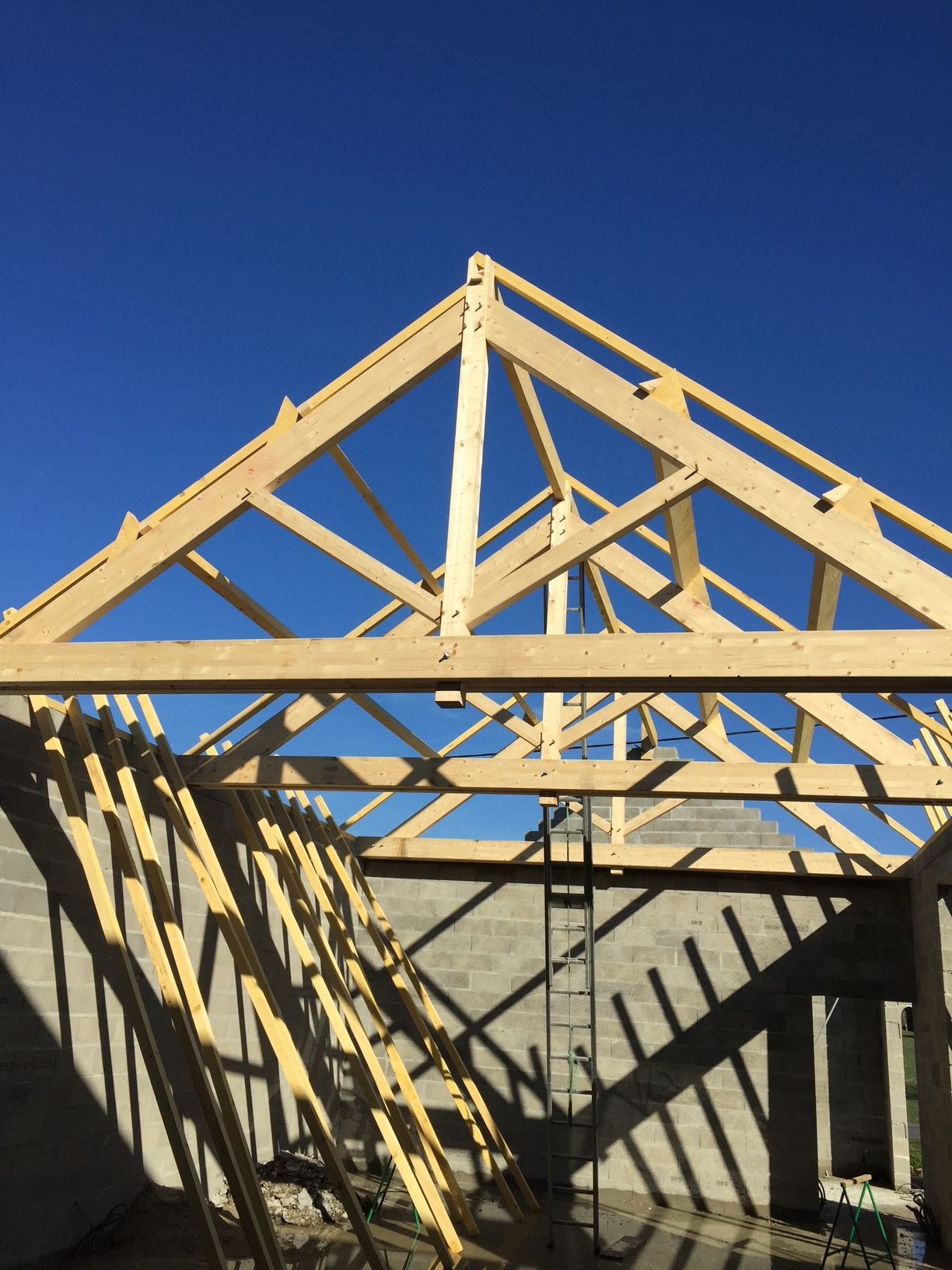 Charpente en bois posée sur une structure de maison en construction