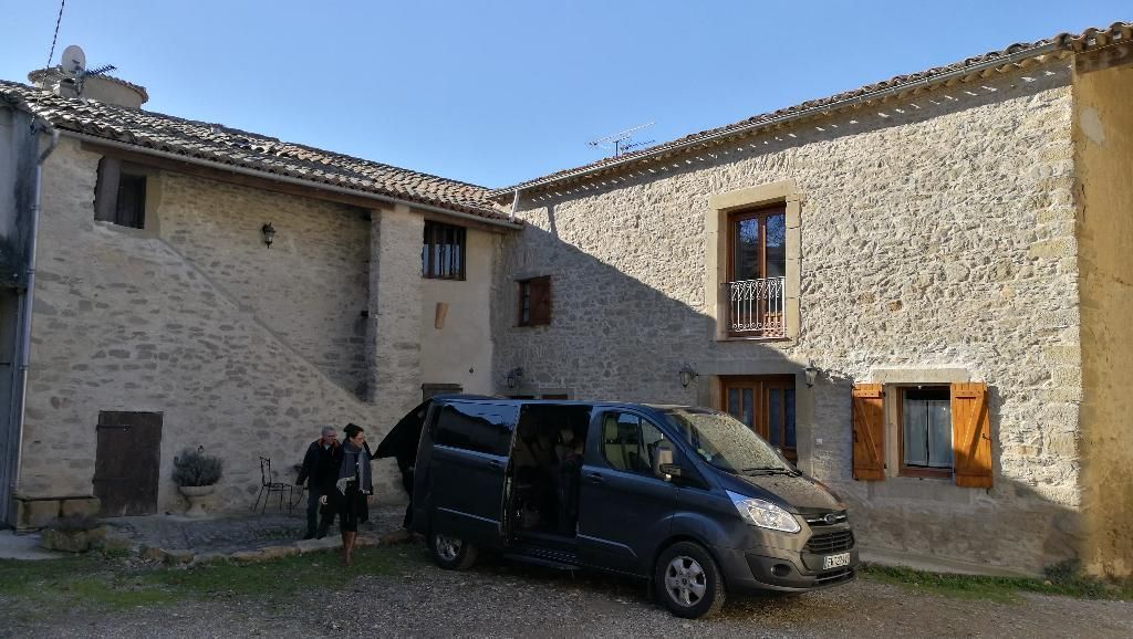 Un minivan garé devant une maison en pierre