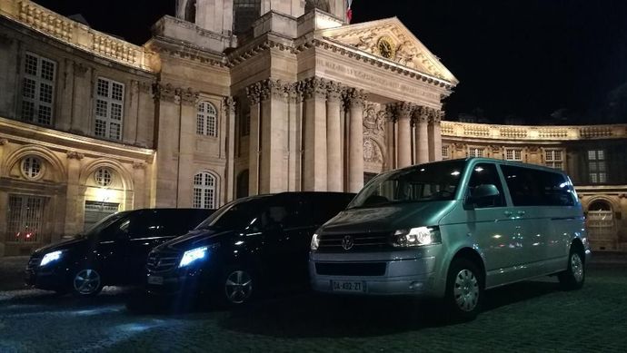 Deux véhicules garés devant un bâtiment illuminé la nuit
