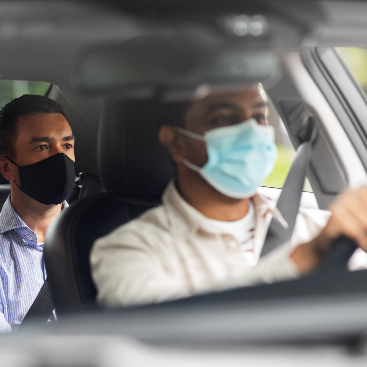 Un passager et un chauffeur, tous deux masqués, sont assis à l’intérieur d’un taxi conventionné