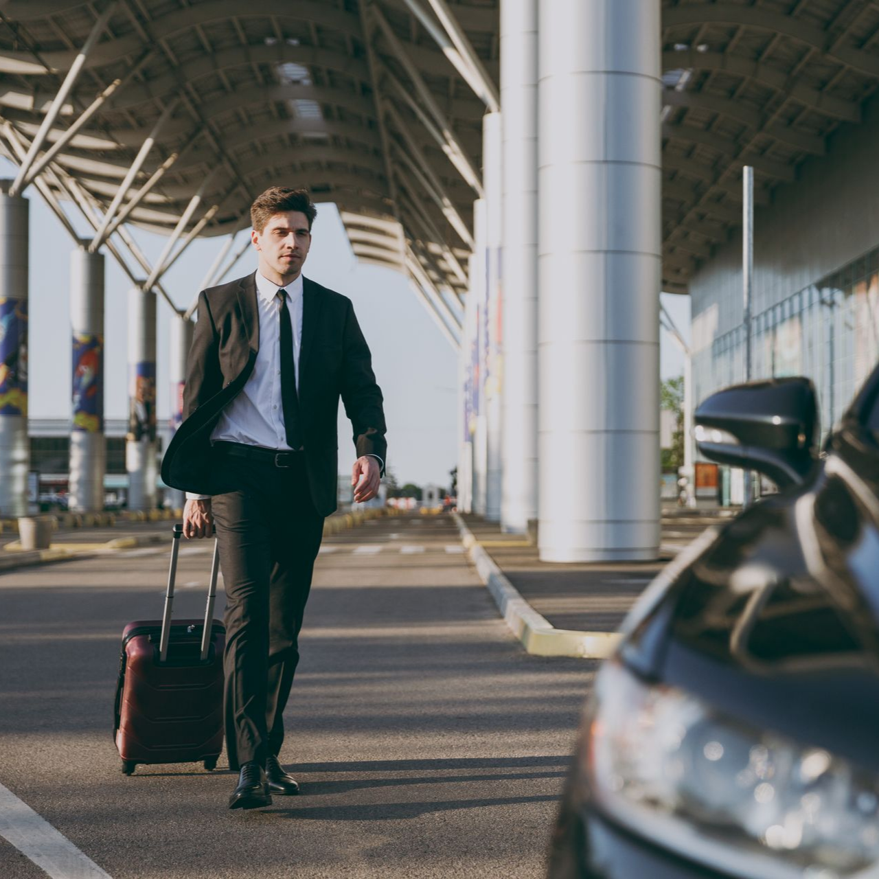 Un homme en costume tirant une valise à l’aéroport