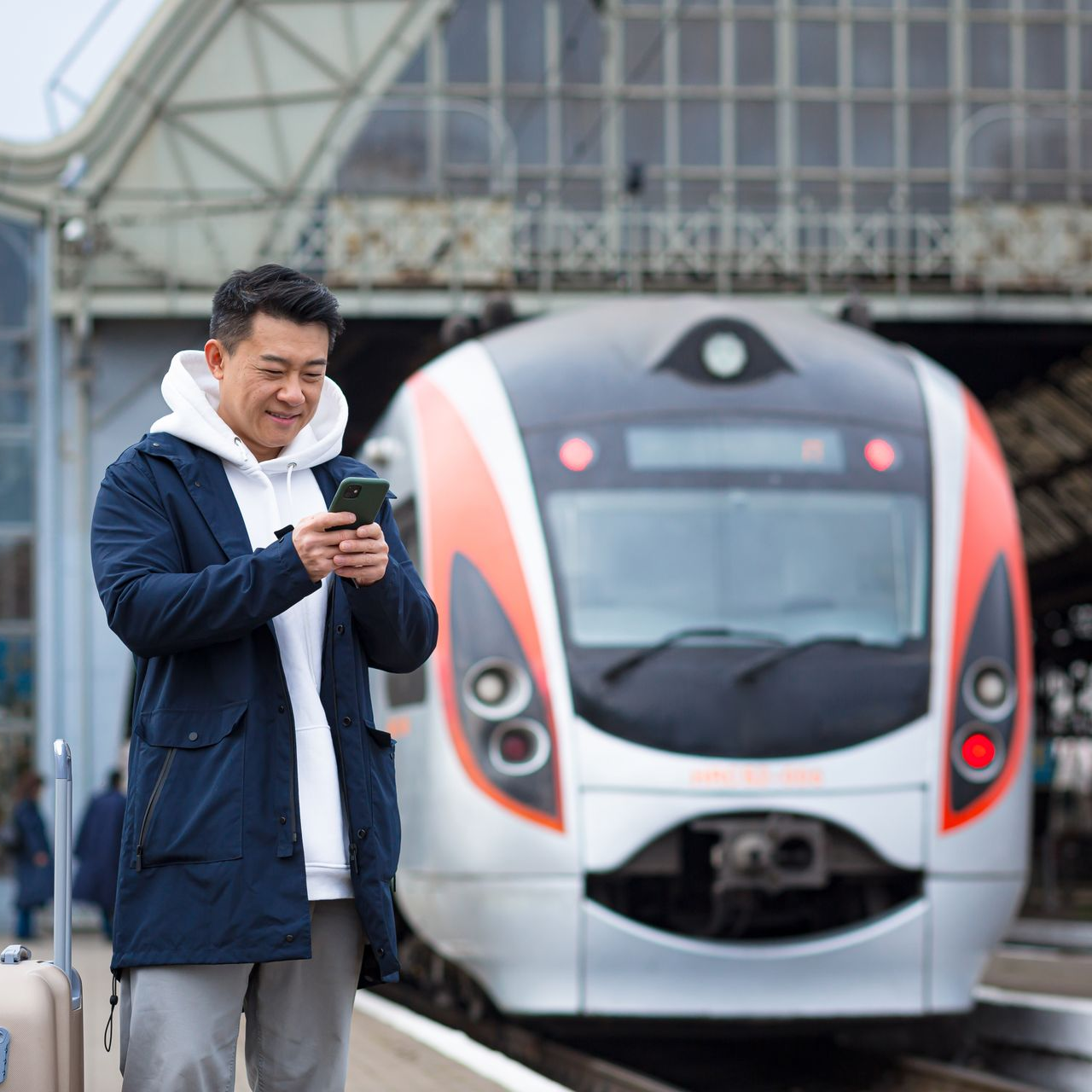 Un voyageur utilisant son téléphone devant un train moderne