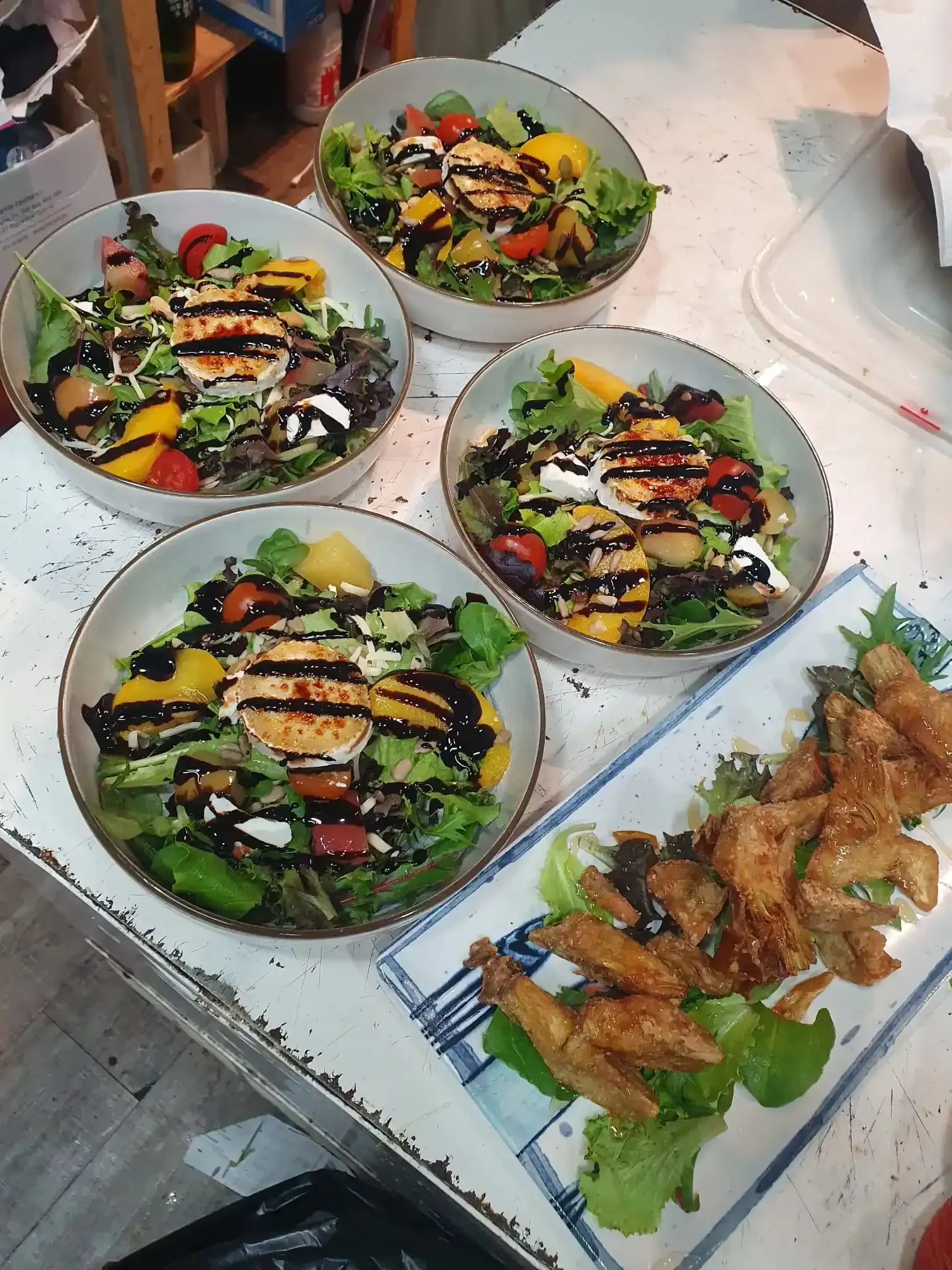 Platos de ensalada colorida y alitas de pollo fritas dispuestos sobre una mesa, listos para servir.