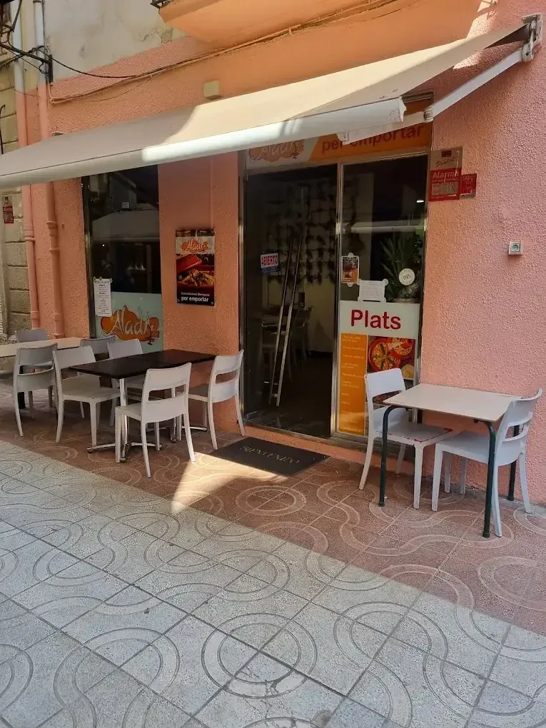 Pequeña cafetería con mesas al aire libre, toldo blanco y un letrero que dice 