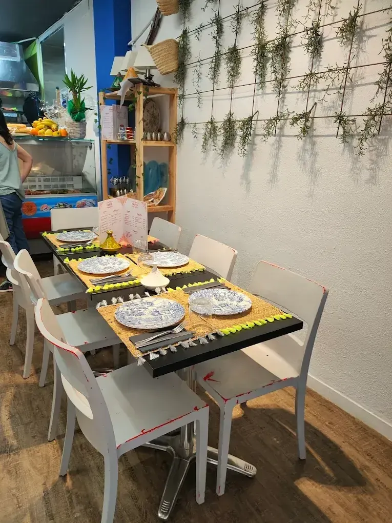Prepara la mesa del comedor con platos, tazas y manteles individuales amarillos en un acogedor café o comedor doméstico.