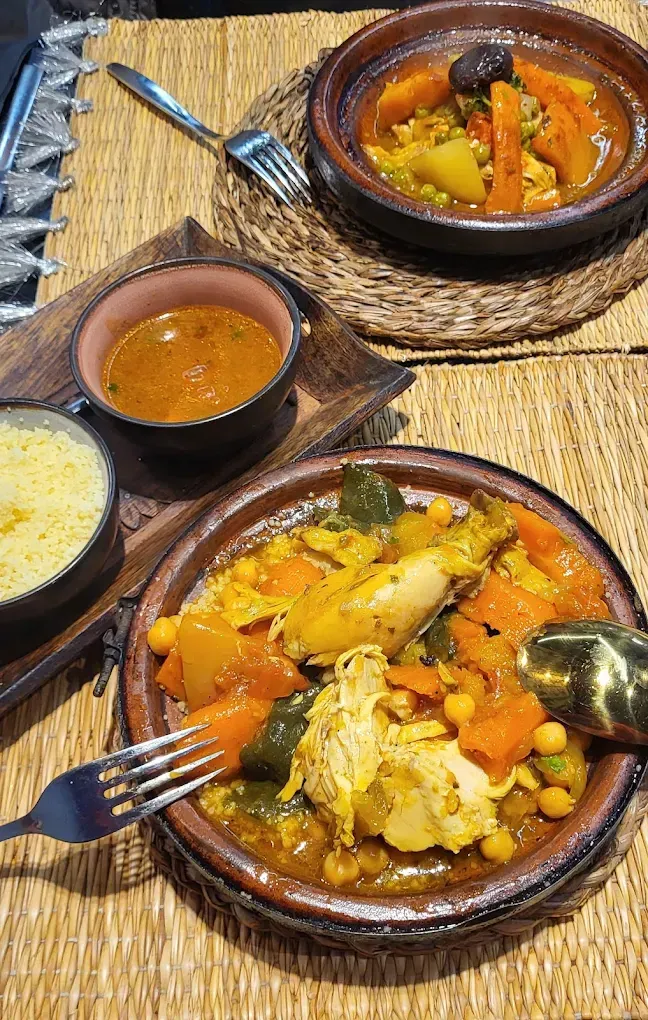 Tres cuencos de guiso colorido con arroz sobre un mantel individual tejido, con tenedores y cucharas.