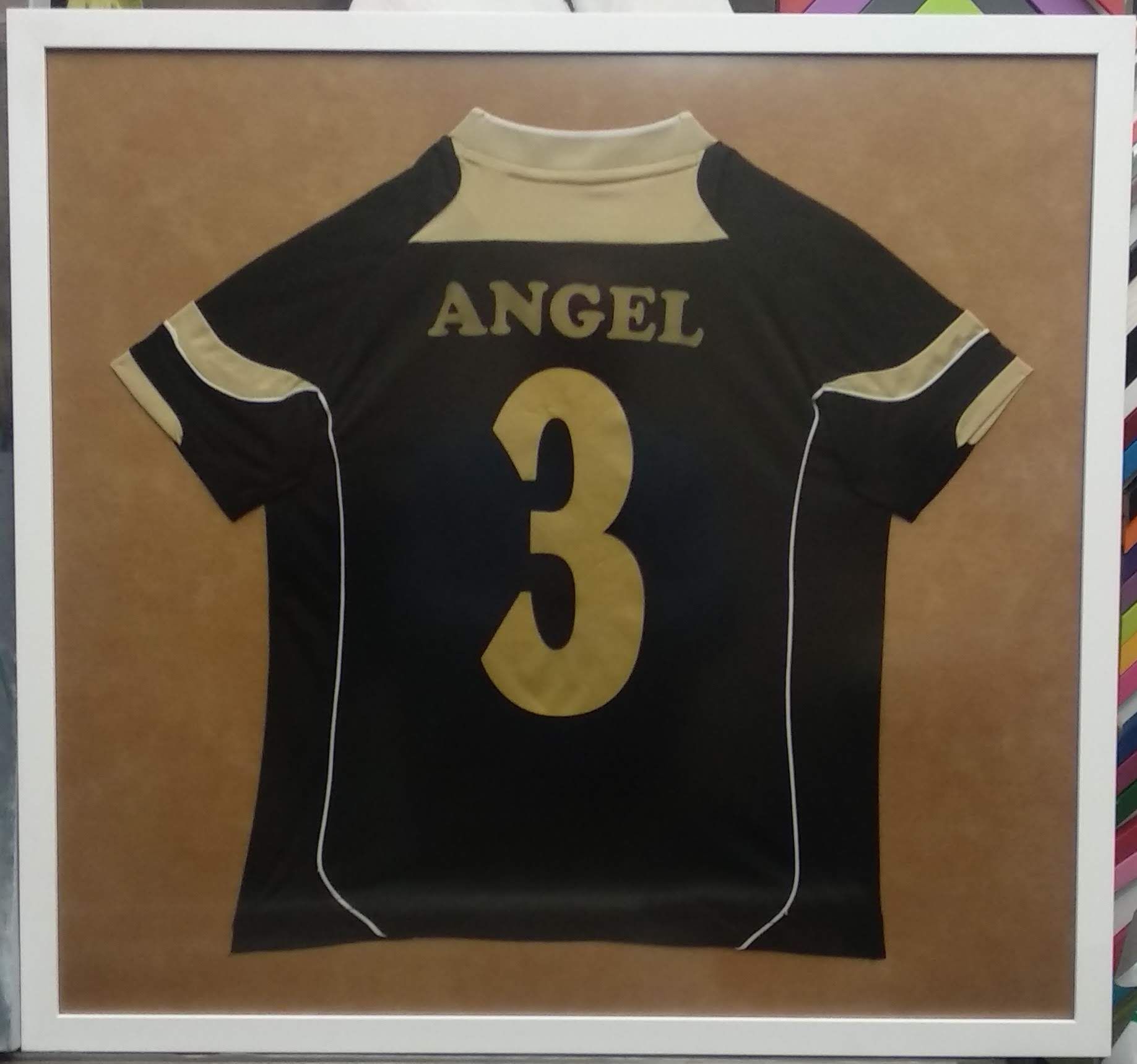 Camiseta deportiva negra y dorada enmarcada en blanco, con 