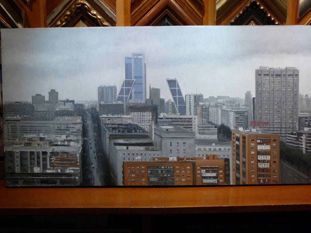 Paisaje urbano bajo un cielo nublado. Rascacielos modernos y edificios antiguos bordean una amplia calle.