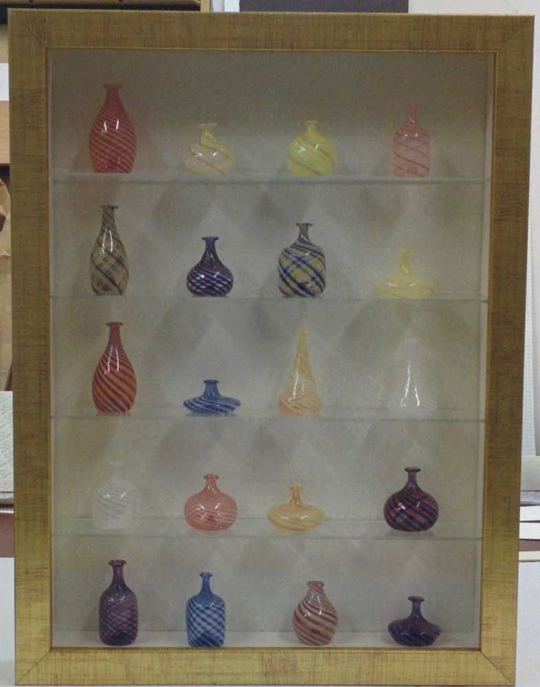 Vitrina de cristal con botellas de cristal de colores y de diversas formas.