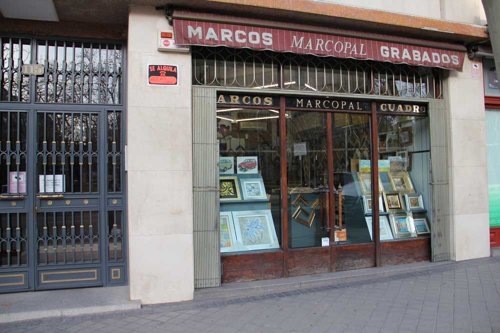 Fachada de tienda con ventanas enrejadas, con publicidad de 