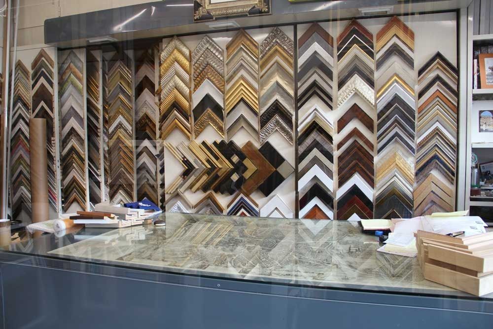 Exposición de diversas muestras de marcos de fotos en ángulo en una tienda de marcos.