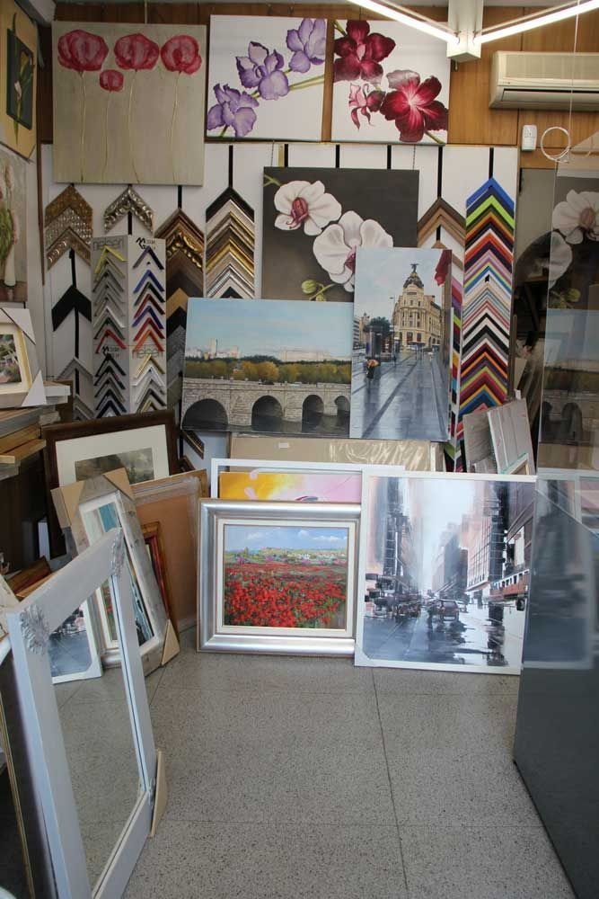 Interior de galería de arte con pinturas enmarcadas y muestras de marcos en exhibición.