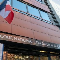 L'entrée du Tribunal national français d'asile à Montreuil, avec un drapeau français flottant sur une façade beige.