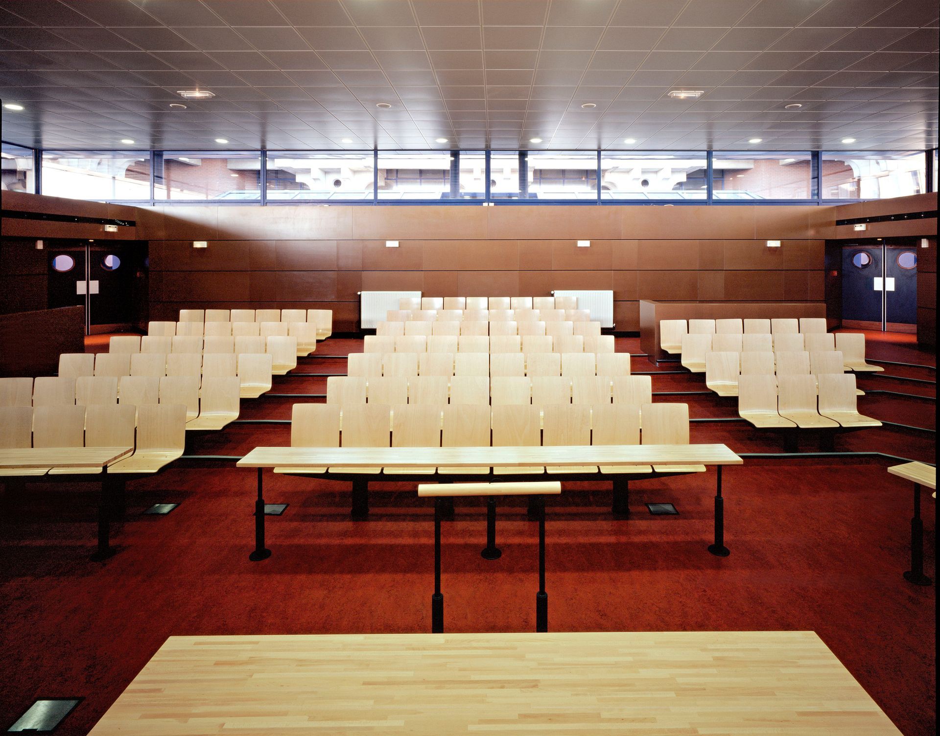Une personne en combinaison orange, menottée, est assise en face d'une personne à un bureau.
