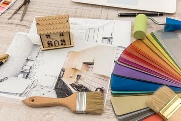 Tablero de inspiración de diseño colorido con pinceles, bocetos, una maqueta de una casa en miniatura