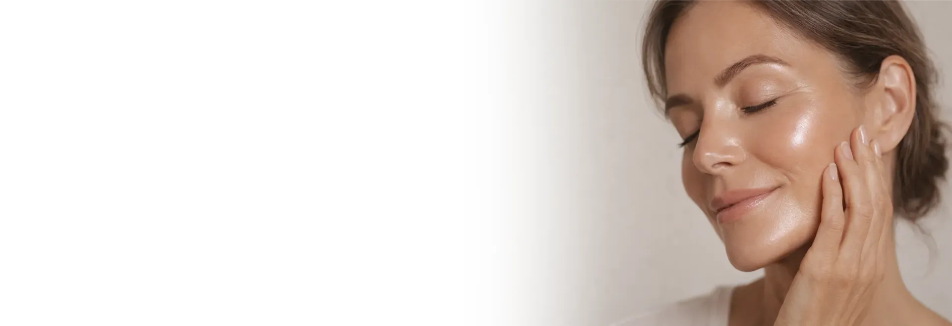 Una mujer en lencería blanca se sienta en un suelo gris, mirando hacia arriba con una expresión pensativa.