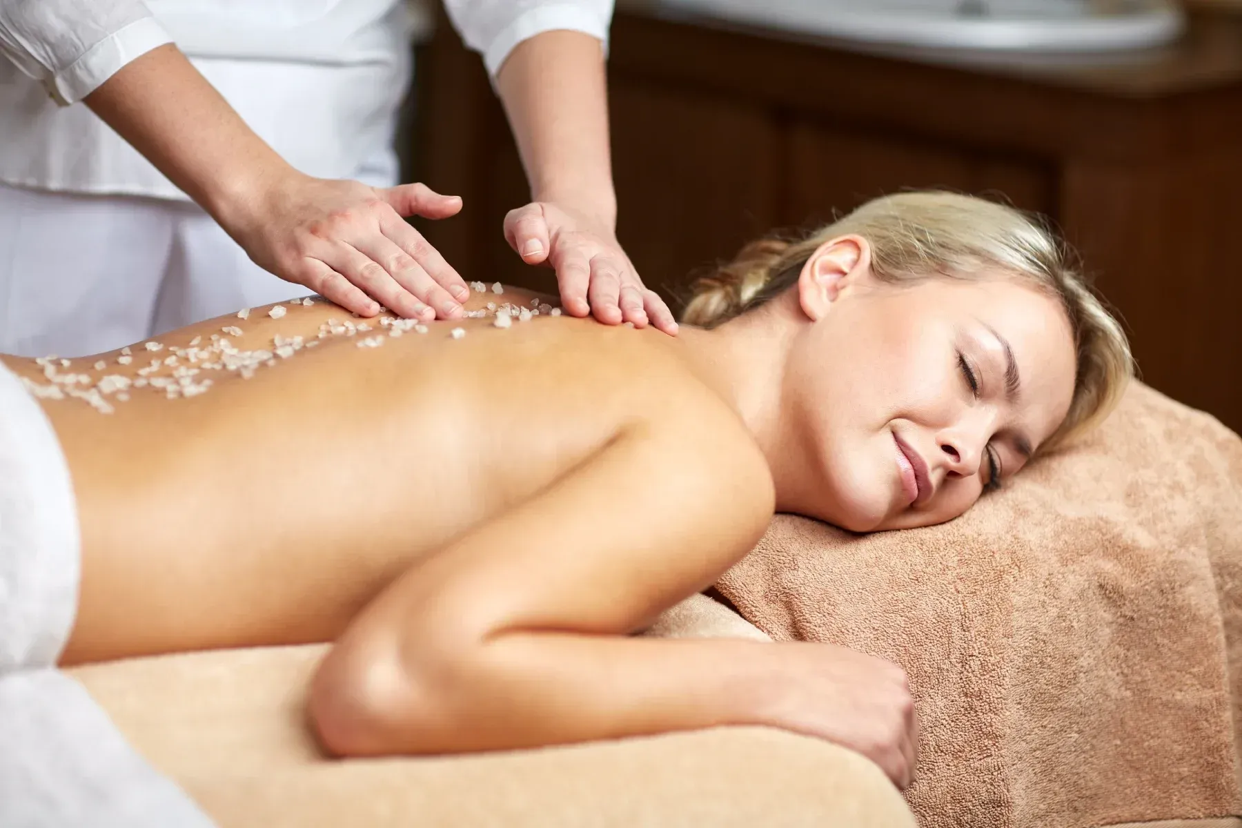Mujer recibiendo una exfoliación de espalda en un spa
