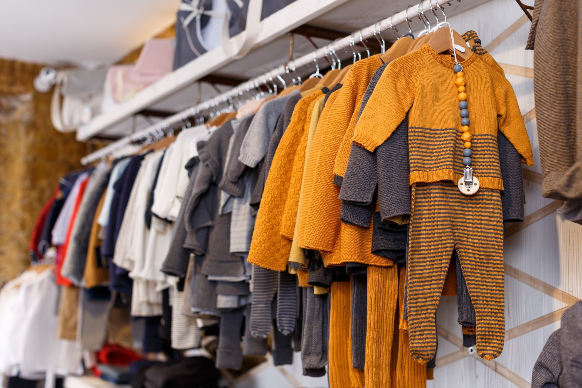 Una fila de ropa de bebé colgada en un perchero en una tienda.