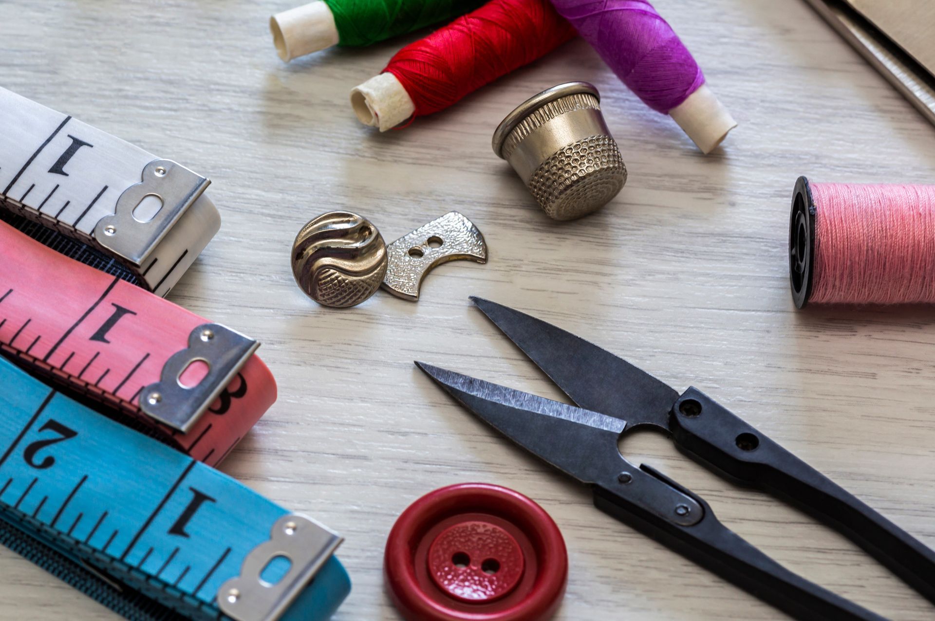 Una mesa cubierta con tijeras, botones, carretes de hilo, dedales y una cinta métrica.