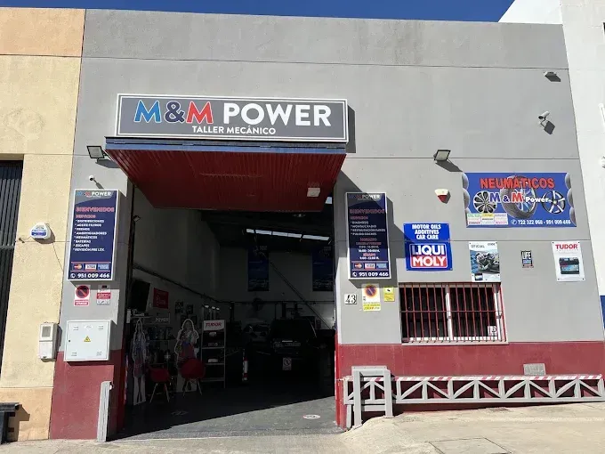 Fachada de M&M Power con entrada de garaje abierta, letreros azules y blancos y un toldo rojo.