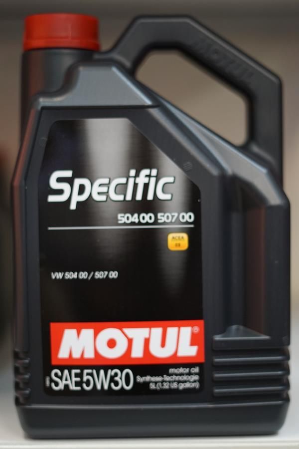 Eine Flasche Motul Specific 5w30 steht auf einem Regal