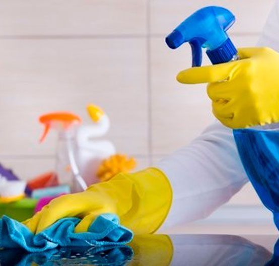 Una persona que lleva guantes amarillos está limpiando un mostrador con una botella de spray.