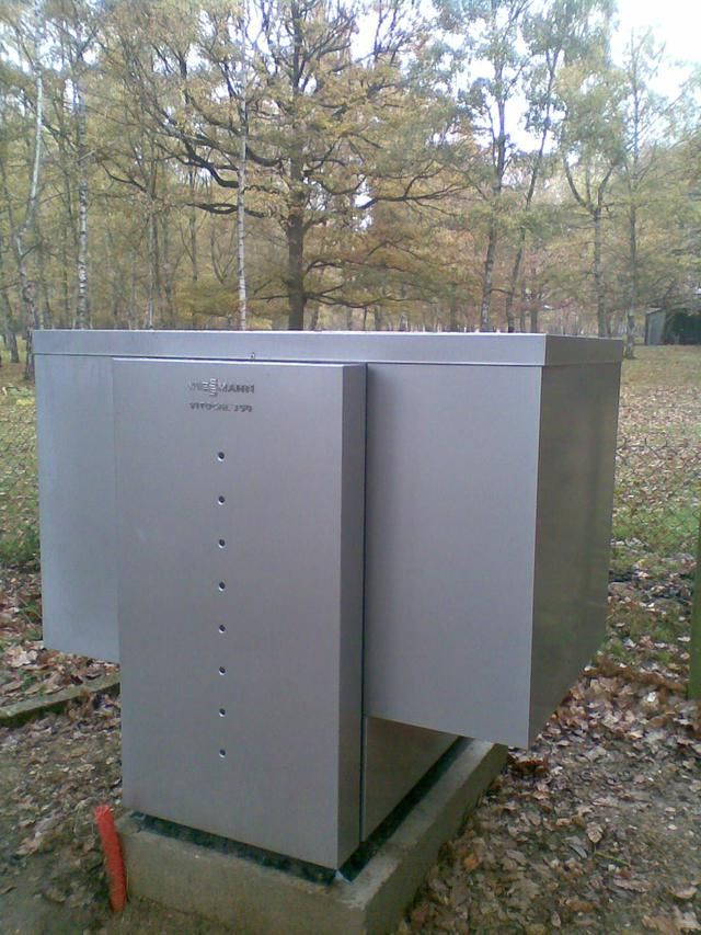 Structure métallique grise et cubique dans un parc sur une base en béton. Arbres en arrière-plan.