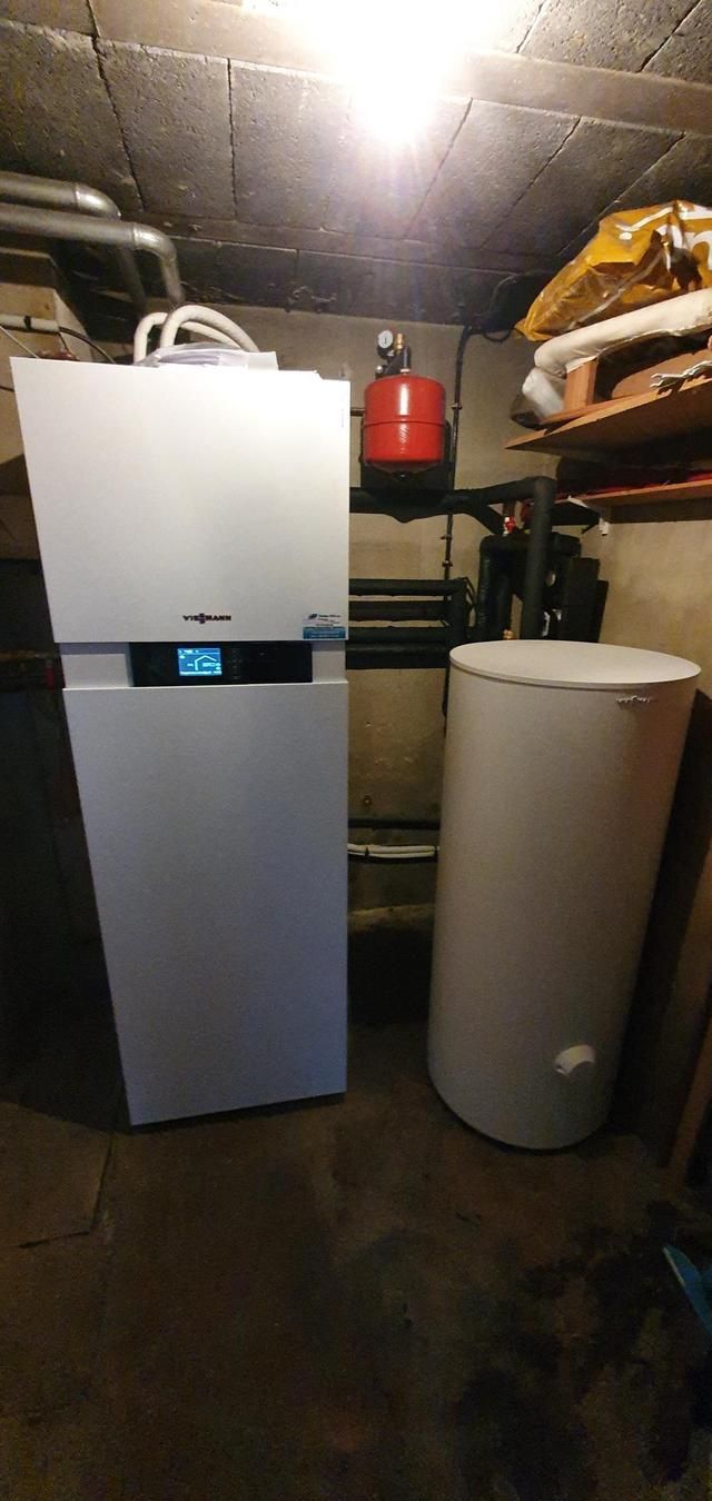Une chaudière blanche et un ballon d'eau chaude dans un sous-sol