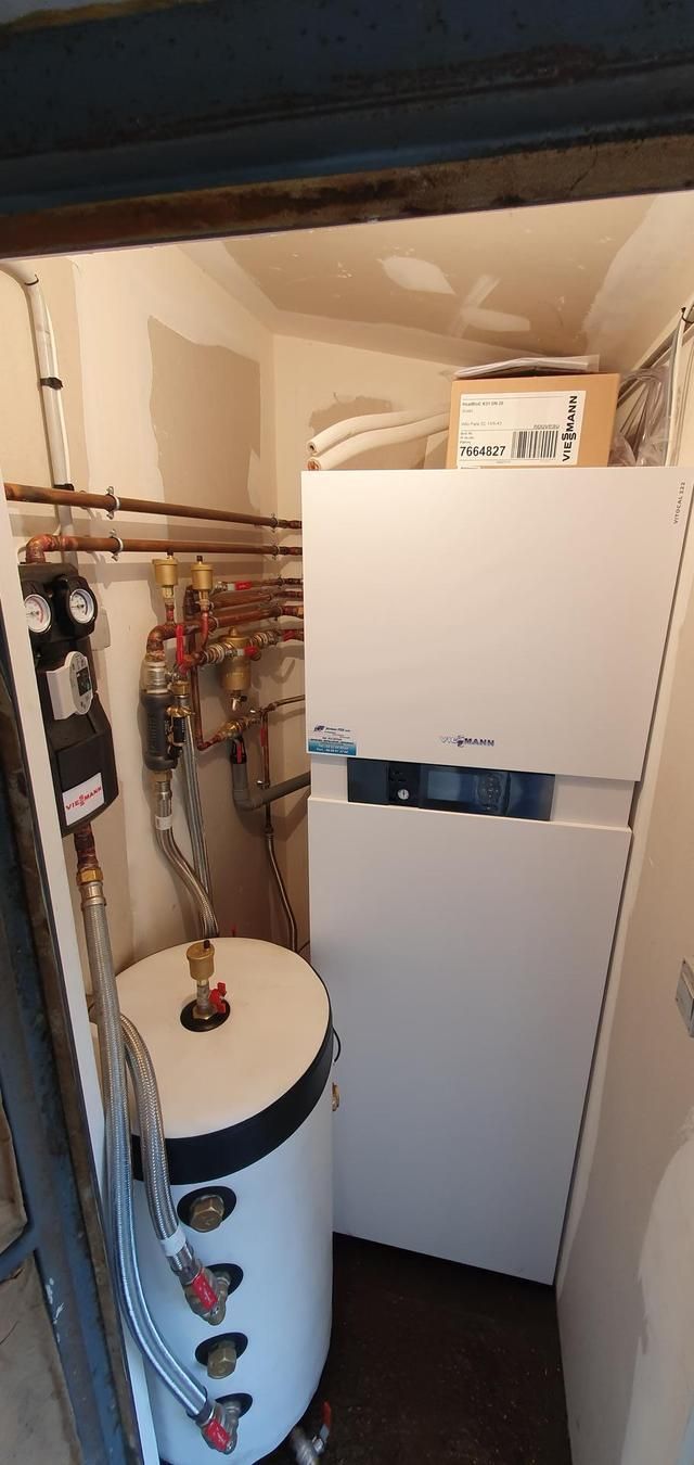 Une chaufferie avec un chauffe-eau, une chaudière et des tuyaux en cuivre