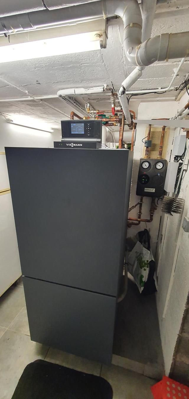 Une salle des machines avec une grande armoire grise, des tuyauteries et des panneaux de commande fixés aux murs